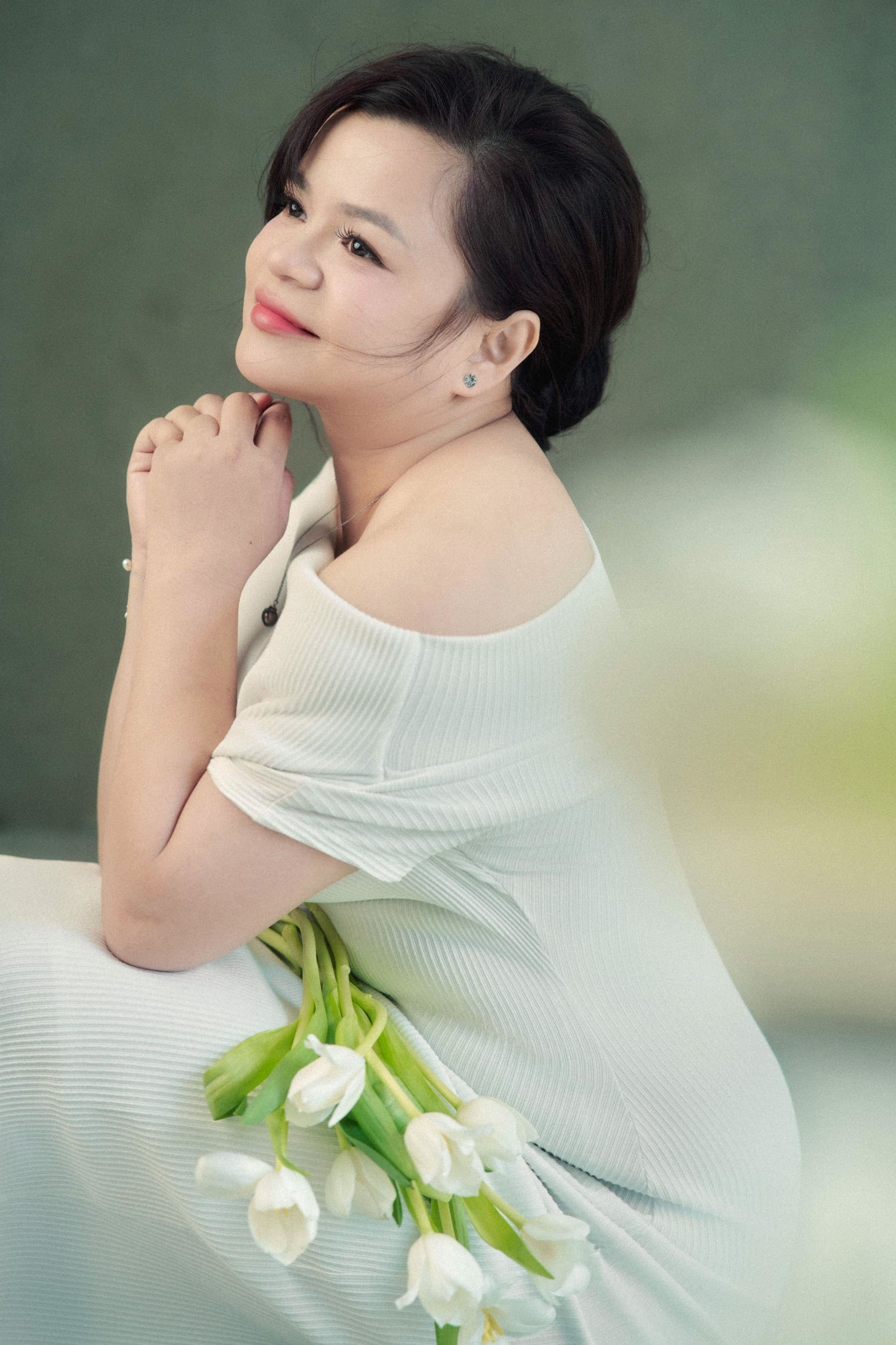 Người phụ nữ chống nhẹ tay lên cằm, mắt khẽ cười về phía xa — ngoảnh lại với chính mình, thấy vẫn còn một người ở đó