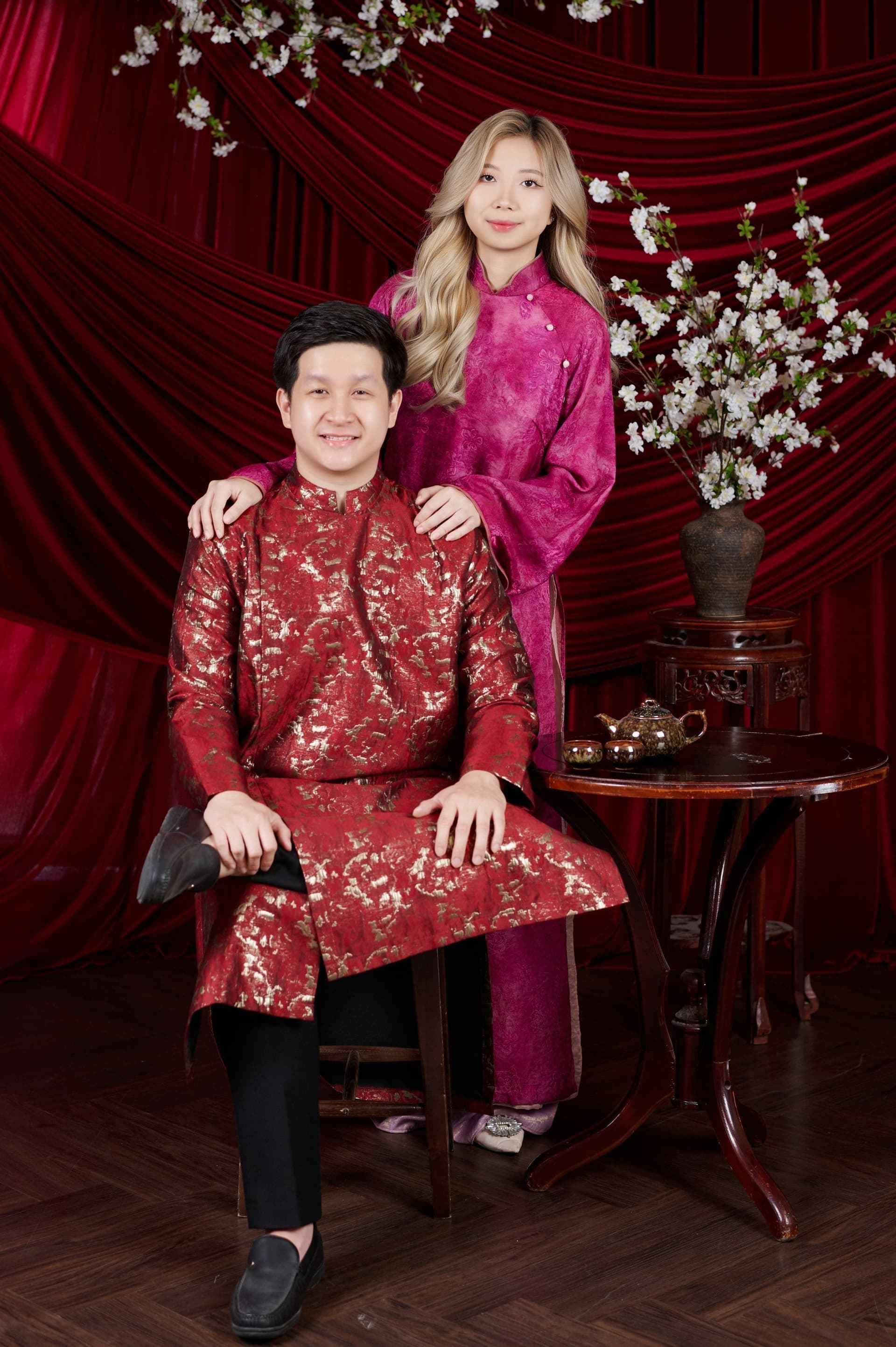 Hai người đứng sát bên nhau trước phông đỏ hoài cổ, ánh mắt trao nhau niềm tin yêu và thấu hiểu sau năm năm đồng hành
