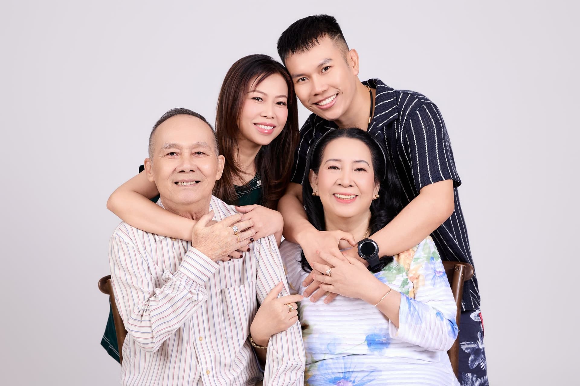 Ba ôm con gái Eva sau lưng, mẹ đứng giữa cười dịu — khoảnh khắc đoàn tụ thân mật của gia đình có con sống xa quê