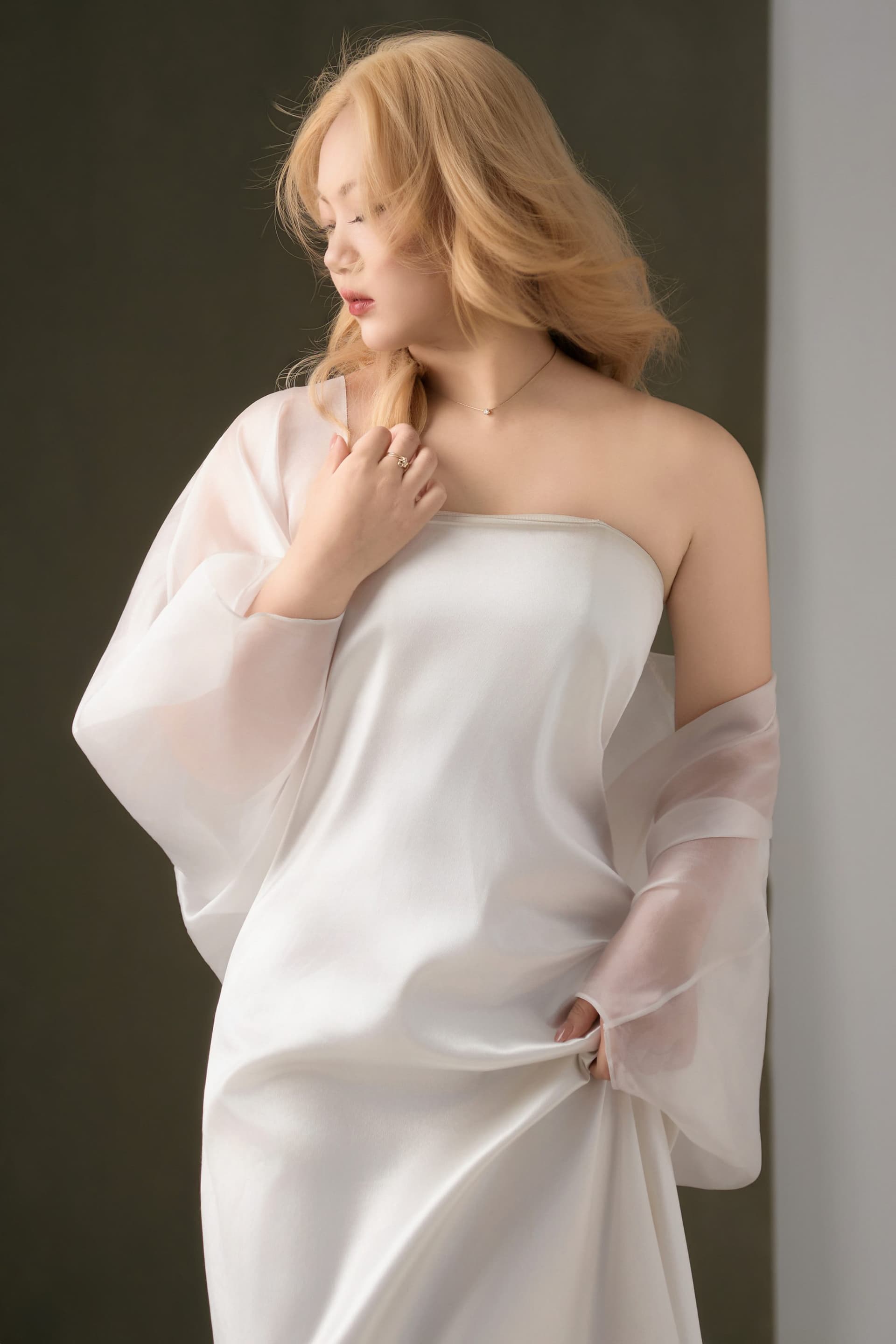 Ri in a white dress standing still, her new hair standing out against a quiet of her own