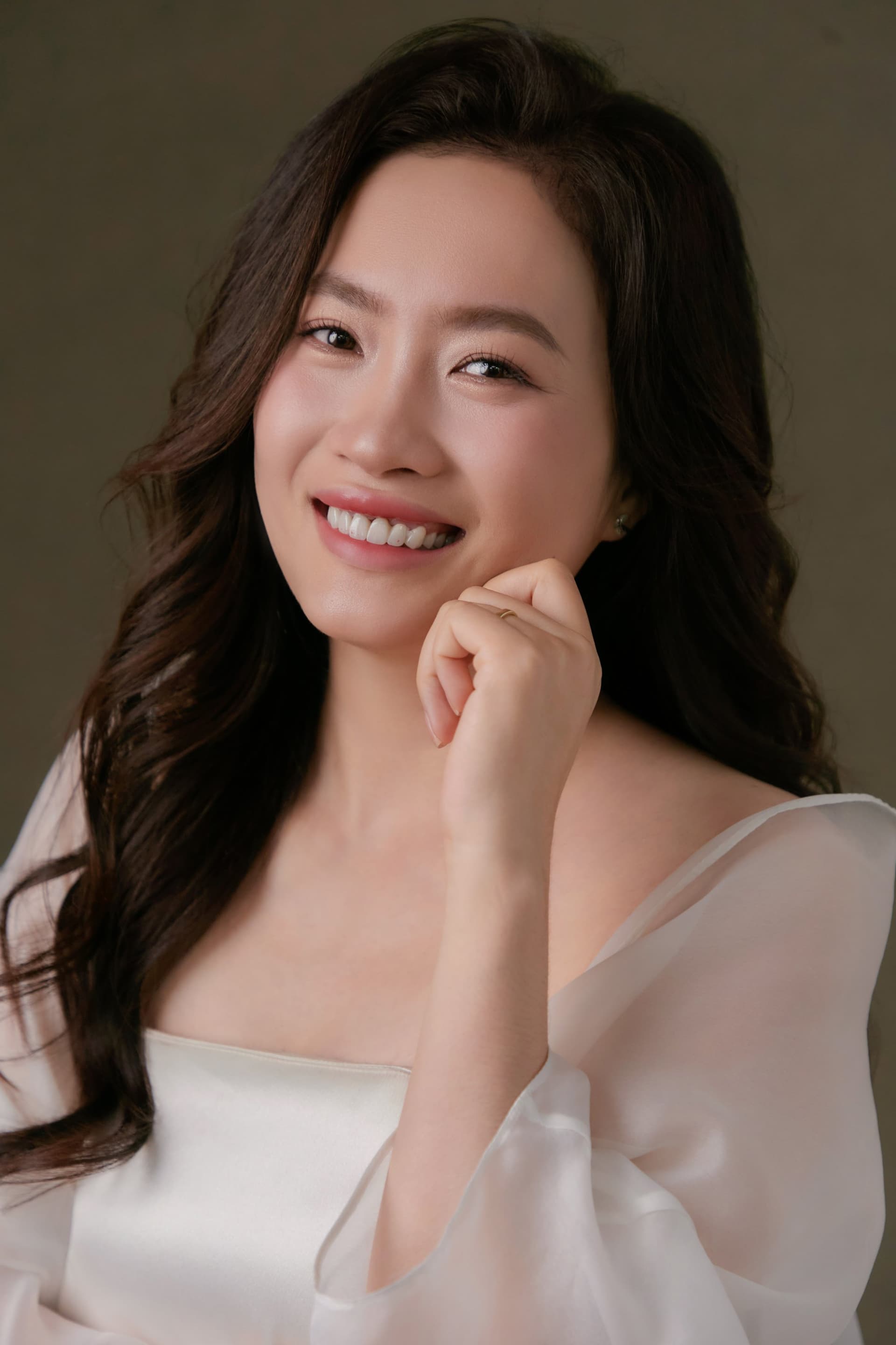 Người phụ nữ cười rạng giữa ánh sáng trong áo trắng mỏng, gương mặt giàu năng lượng