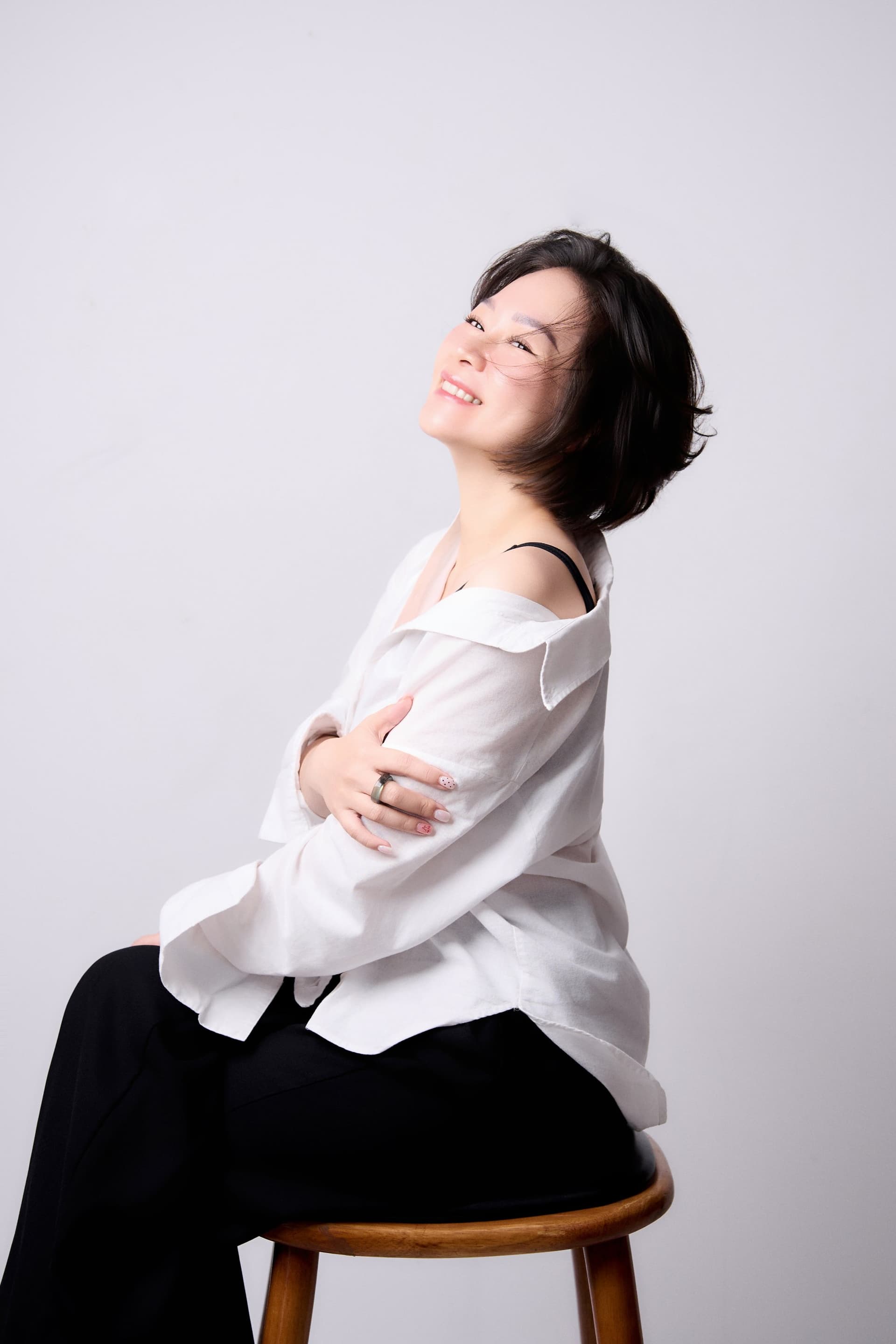 Bảo Ngọc Vũ tựa lưng vào ghế ngửa đầu cười rạng rỡ và tràn đầy sức sống tuổi 40