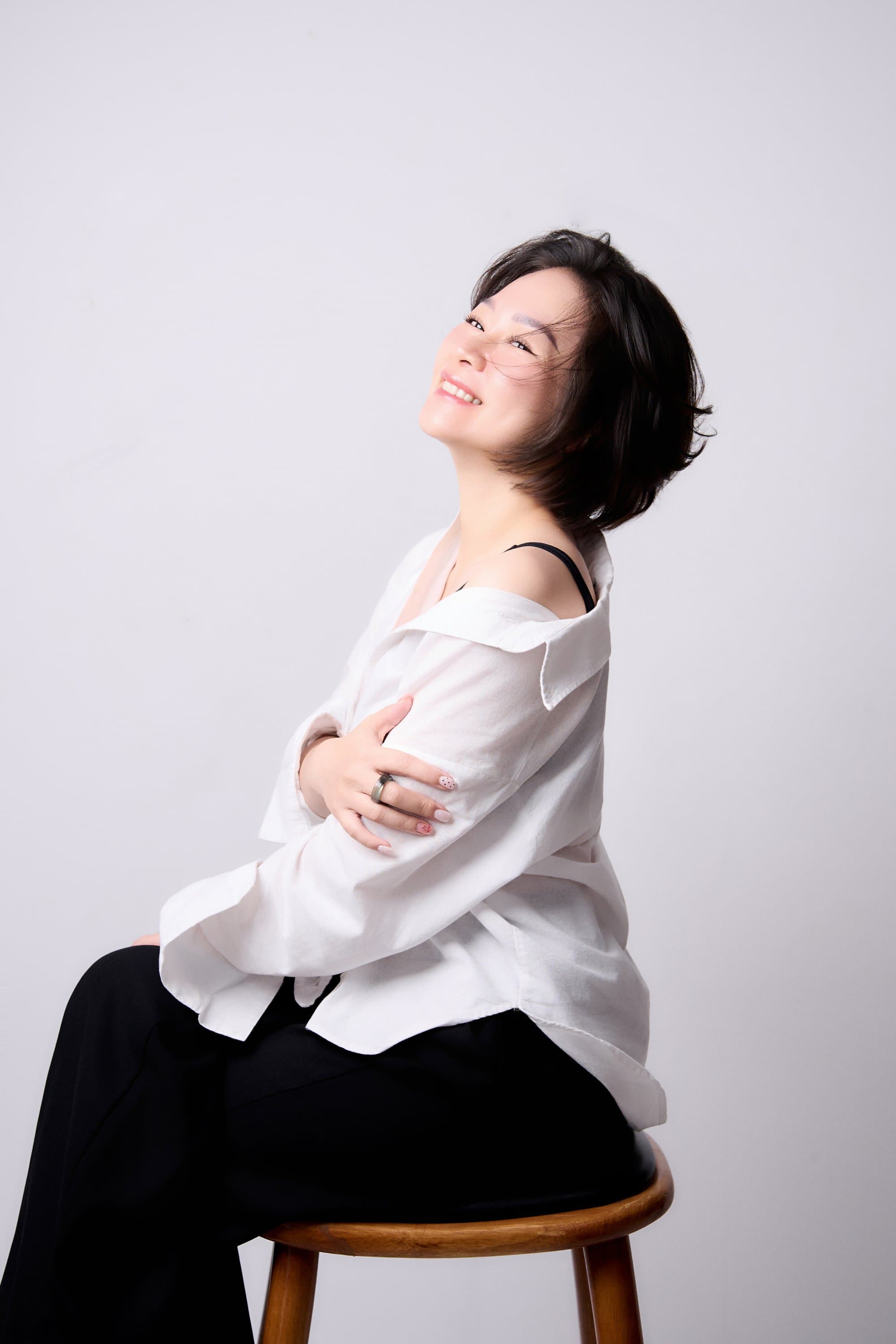Bảo Ngọc Vũ tựa lưng vào ghế ngửa đầu cười rạng rỡ và tràn đầy sức sống tuổi 40