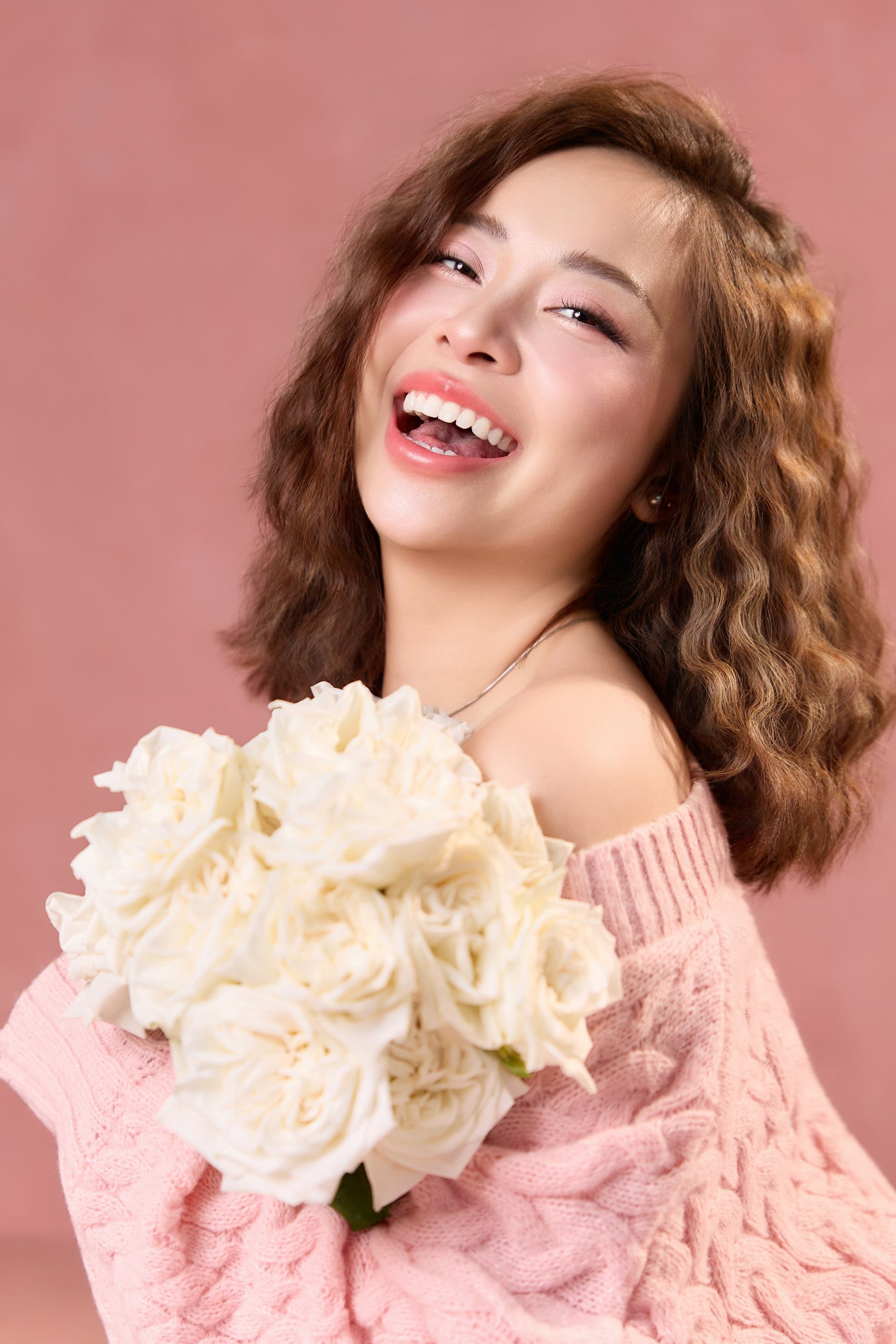 Trúc Anh ôm bó hoa hồng trắng sát ngực, nụ cười rạng rỡ đầy năng lượng tích cực