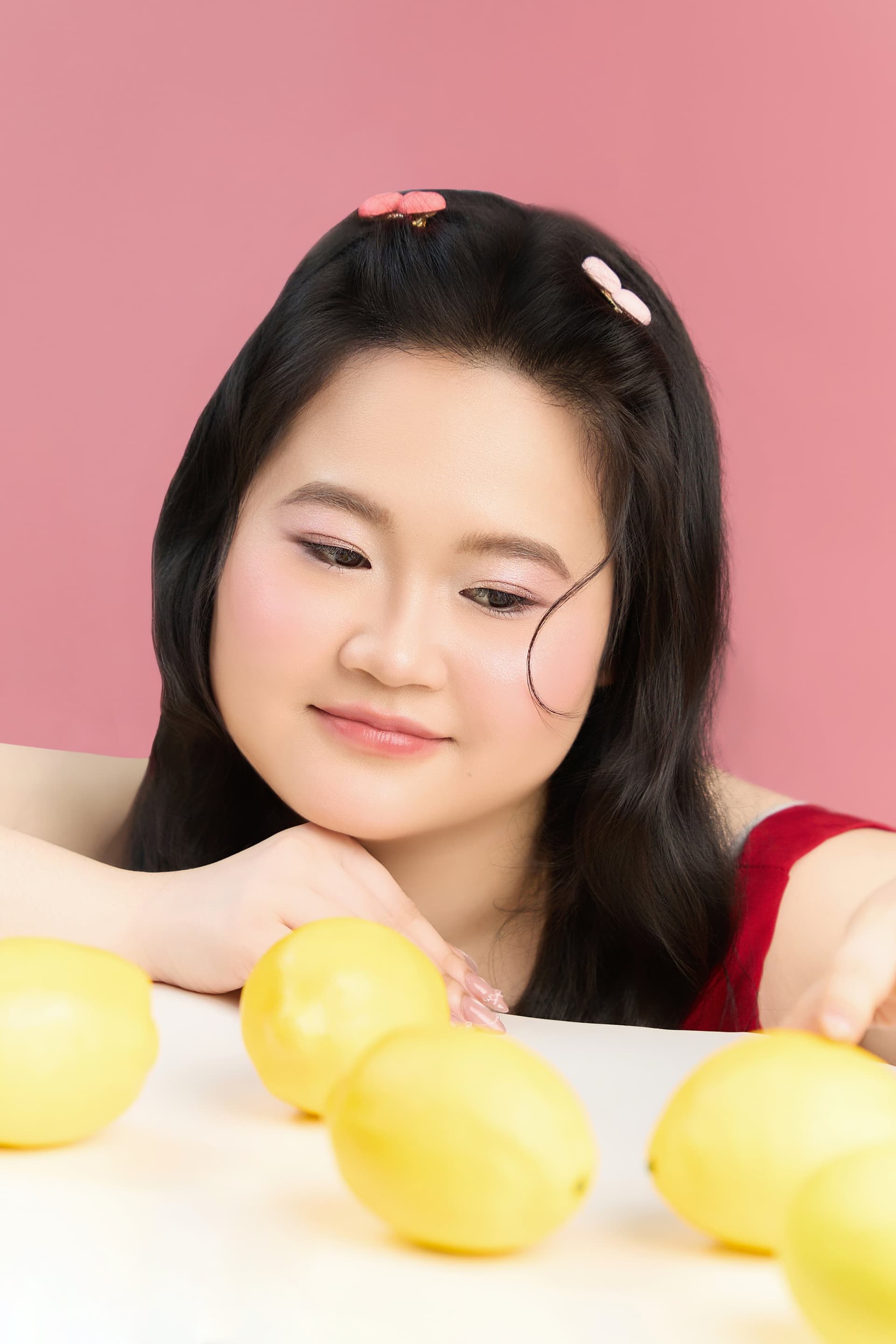 Phương với biểu cảm dịu dàng khẽ nhìn xuống những trái chanh vàng tươi đặt trên bàn