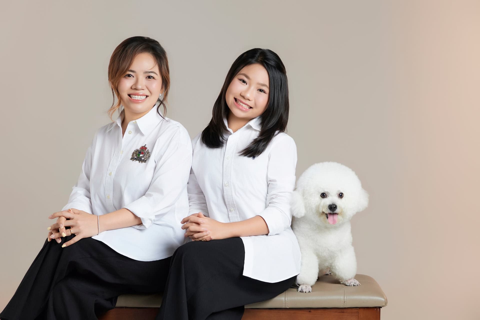 Cả nhà cùng cười rạng rỡ bên chú chó trắng nhỏ trong studio