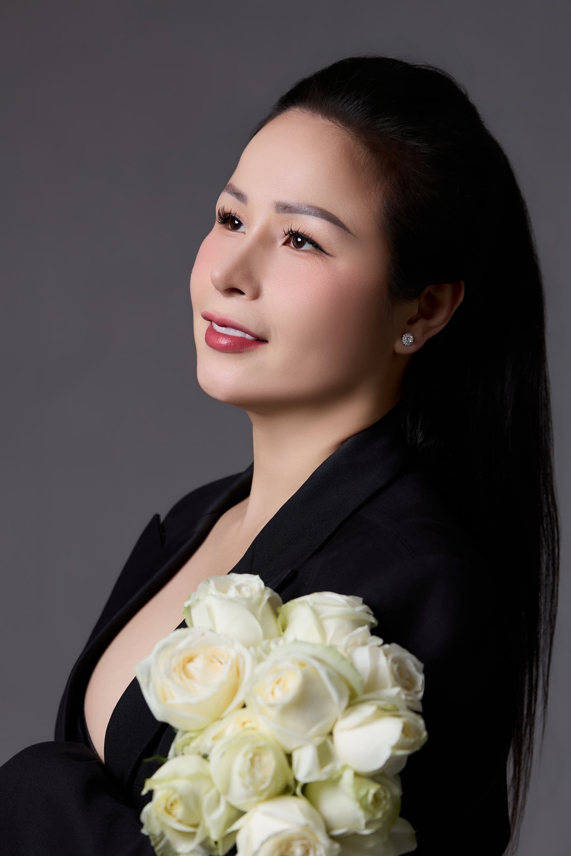Người phụ nữ trong vest đen, dáng nghiêm, mắt nhìn xa — chân dung một người đã tự đứng nhiều năm trước khi mở được tiệm của mình