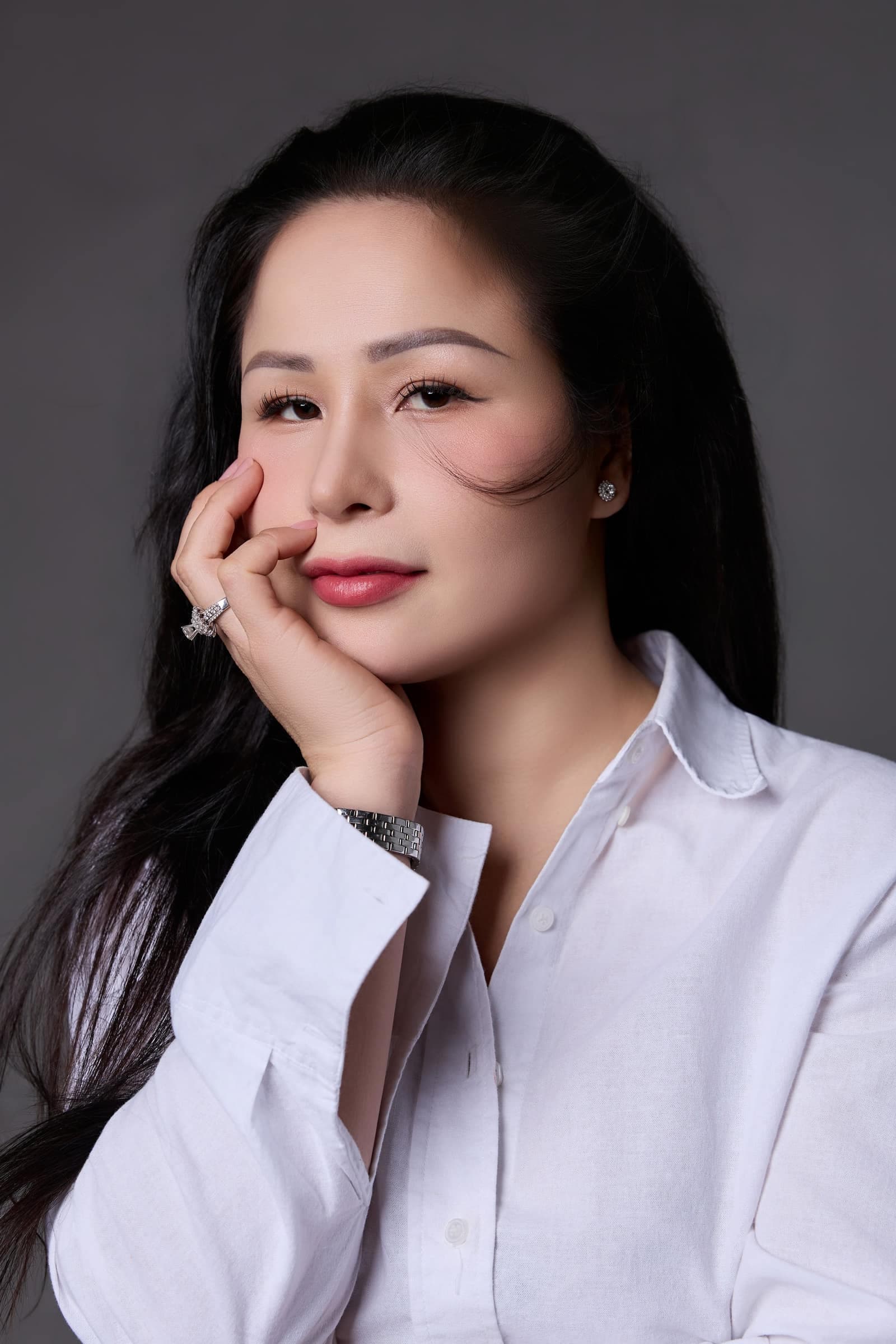 Người phụ nữ áo sơ mi trắng, một tay khẽ chống cằm, mắt nhìn nghiêng — khoảnh khắc tự nói với mình "sống hết mình"