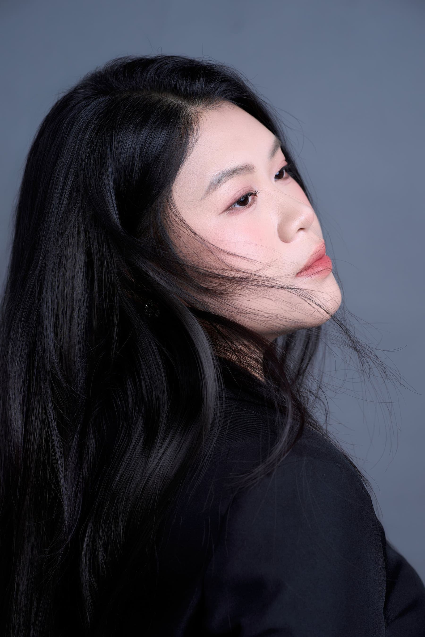 Người phụ nữ nhìn xa, tóc đen buông vai, gương mặt trầm tư — đứng trước cột mốc mới sắp làm mẹ