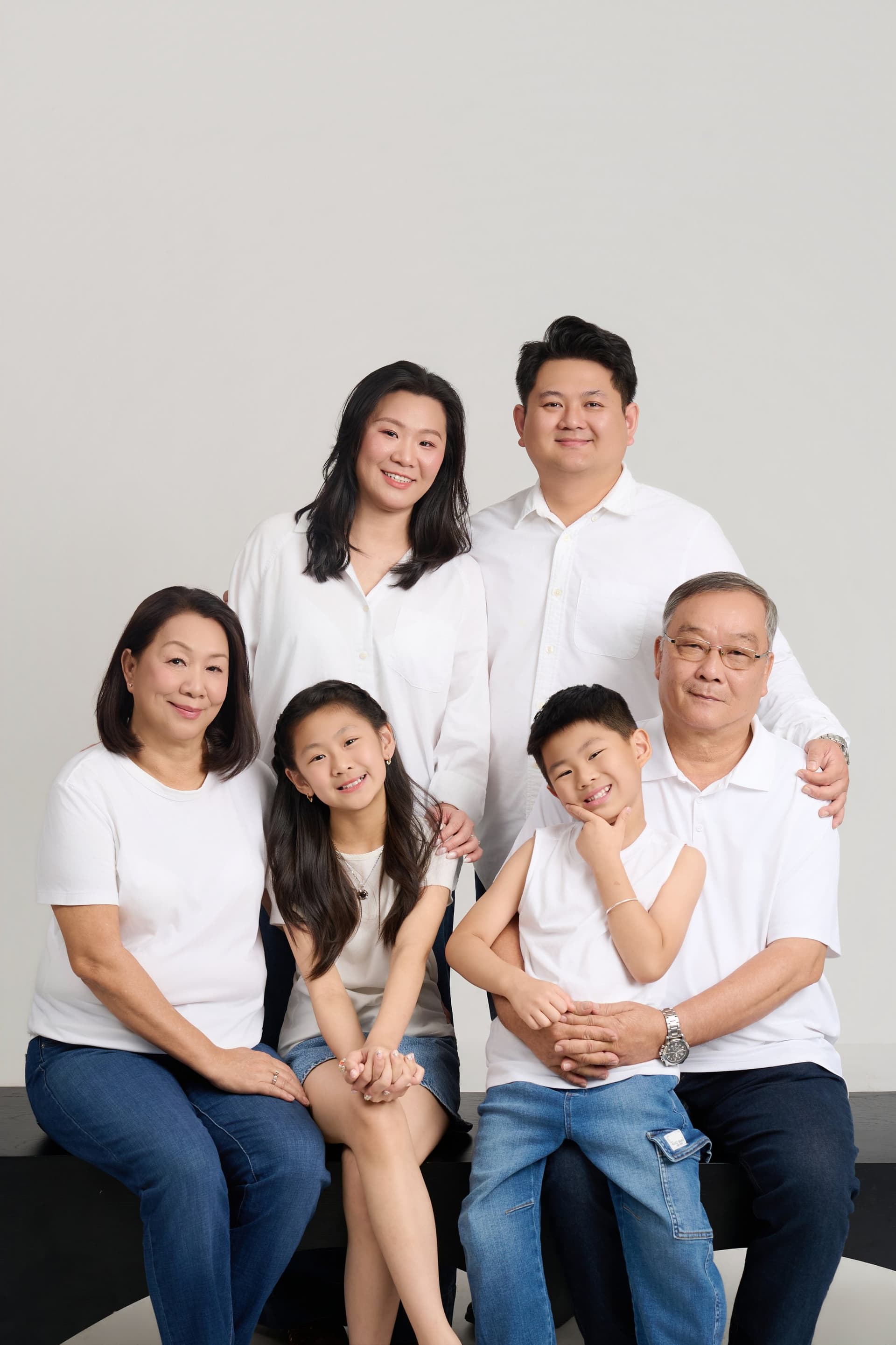 Cả gia đình gồm cô chú và con cháu mặc áo sơ mi trắng đứng ngồi quây quần bên nhau cười hạnh phúc