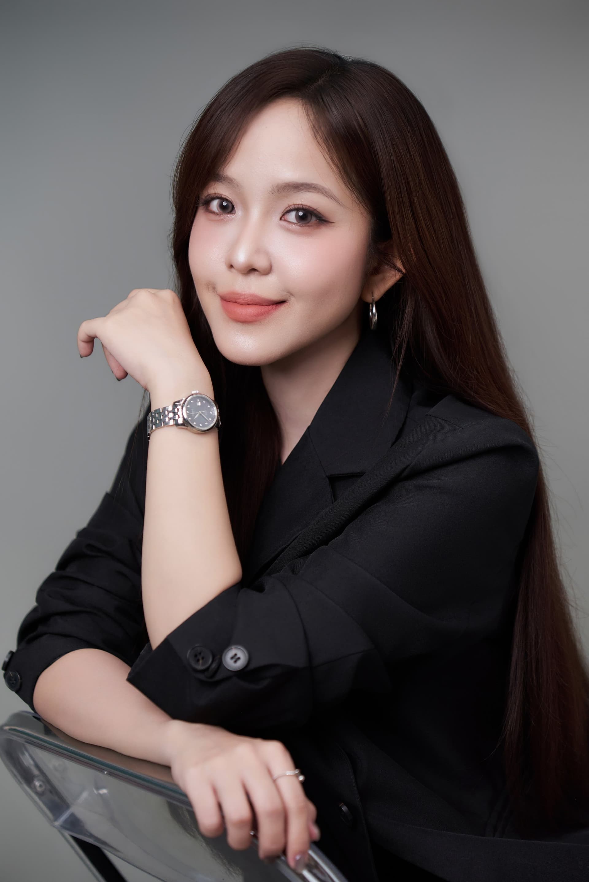Lê Vy mặc blazer đen lịch lãm trên phông xám, phong cách trẻ trung năng động và tự tin của một content creator