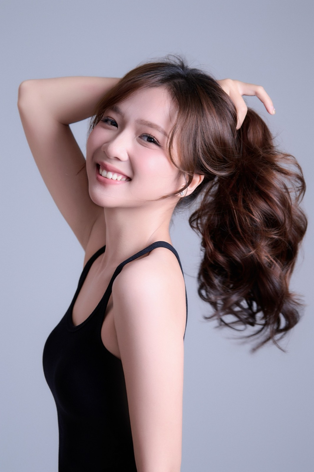 Sắc Ly cười rạng rỡ, tóc cột cao bay nhẹ trong gió, vai trần áo tank top đen — vẻ ngoài tươi tắn của một người trẻ đứng trước máy quay mỗi ngày.