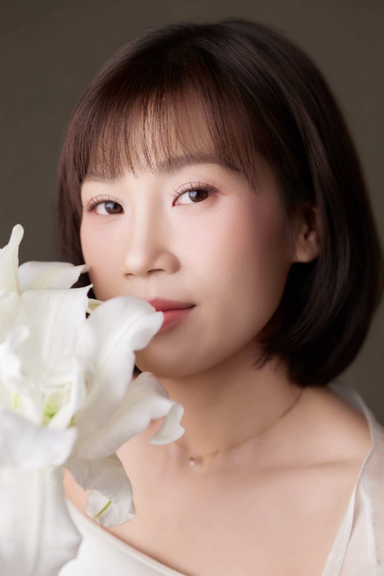 Chị Vy Mi cận mặt, tay đưa cánh hoa gần môi, mắt nhắm nhẹ