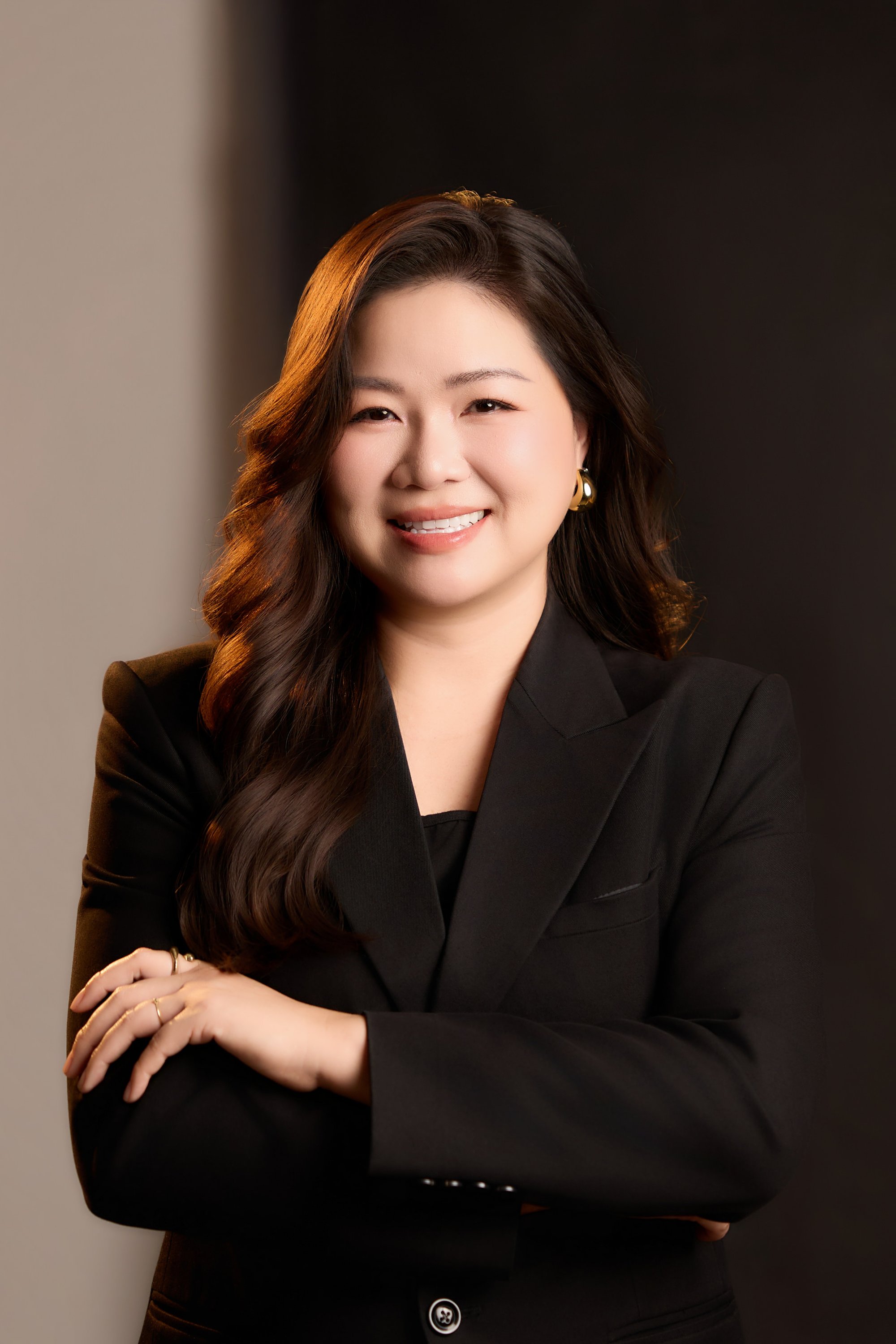 Trang Ngo đứng tay khoanh trước ngực, cười nhẹ — gương mặt của một người vẫn có mặt, vẫn đi qua những ngày cần làm
